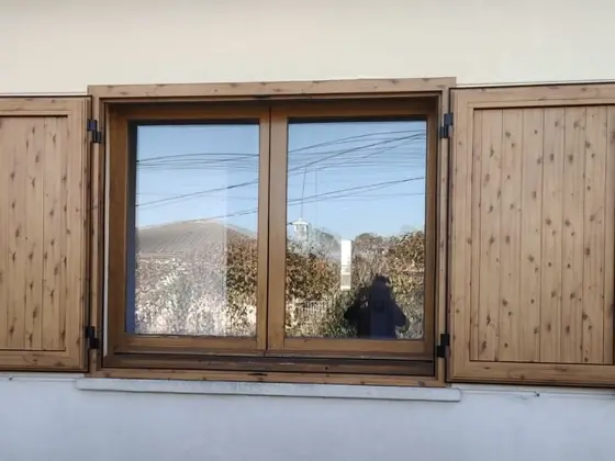 Ventana con acabado de madera y contraventanas
